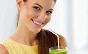 Person smiling drinking green juice