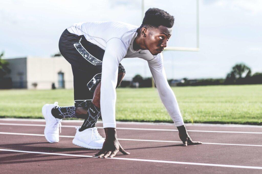 person kneeling preparing to run on an outdoor track