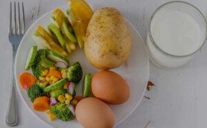 plate with vegetables, eggs, fruit, and a glass of milk