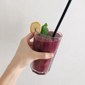 person holding a dark purple fruit smoothie