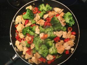 a pan full of chicken, broccoli and red peppers
