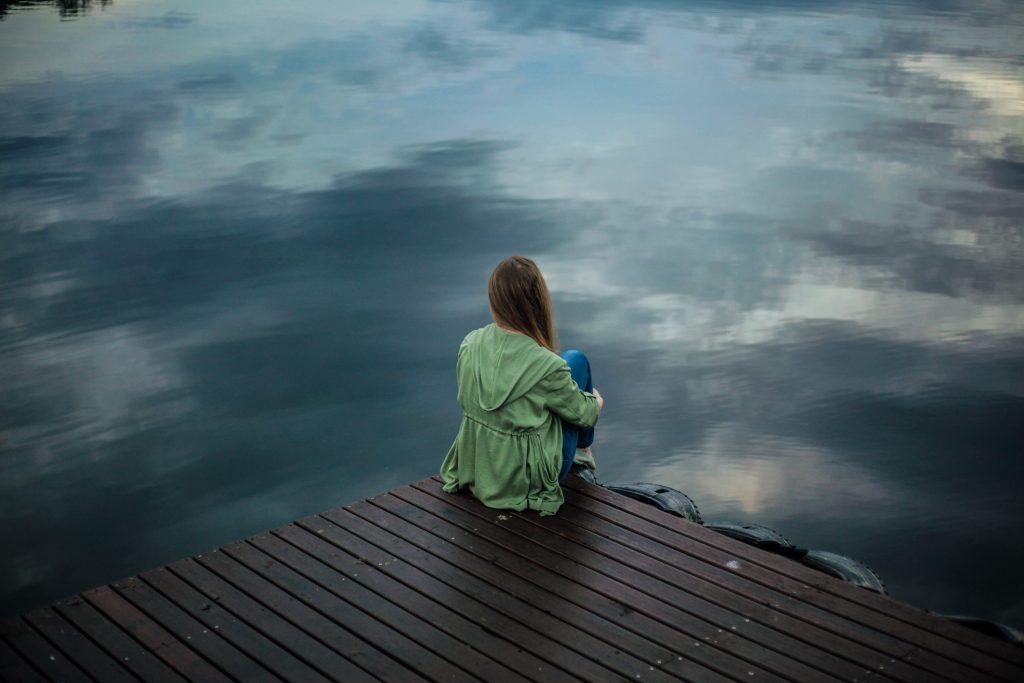 person sitting on a dock by a lake