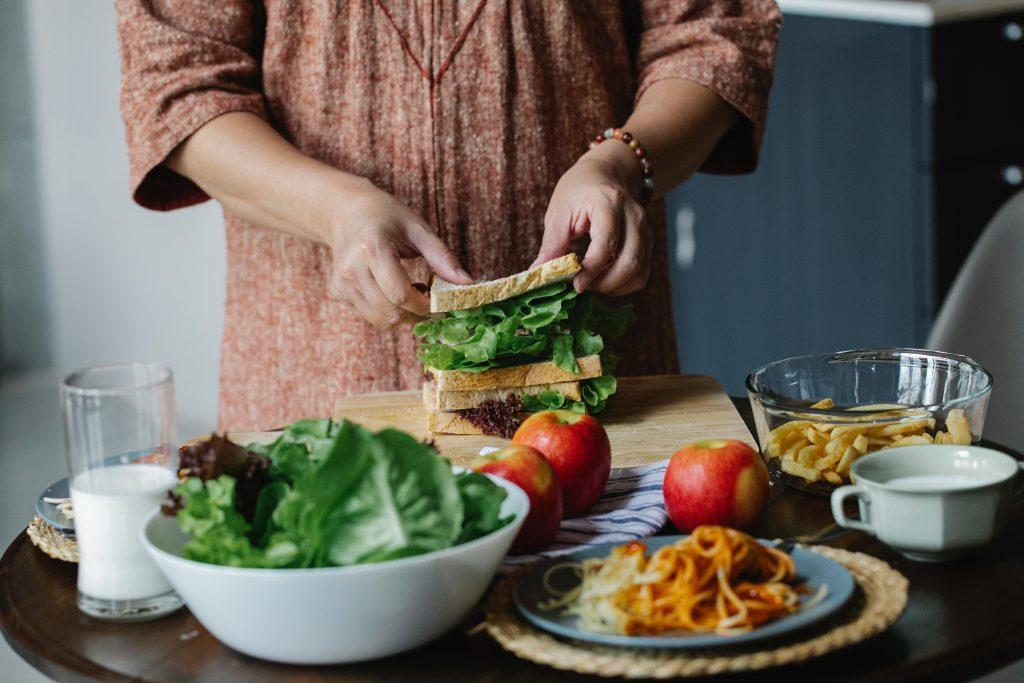person making a sandwich with apples, spinach and milk on the table