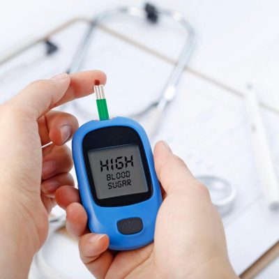 hand-holding-blood-glucose-meter-measuring-blood-sugar-background-is-stethoscope-chart-file