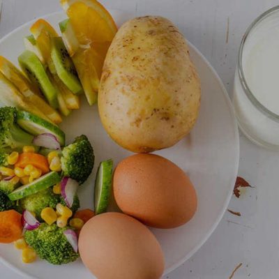 plate with vegetables, eggs, fruit, and a glass of milk
